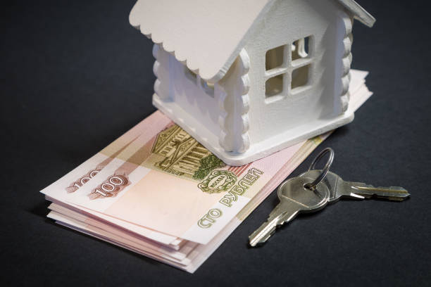 A bundle of Russian rubles, the keys to a future home and a mock-up of house on a black background